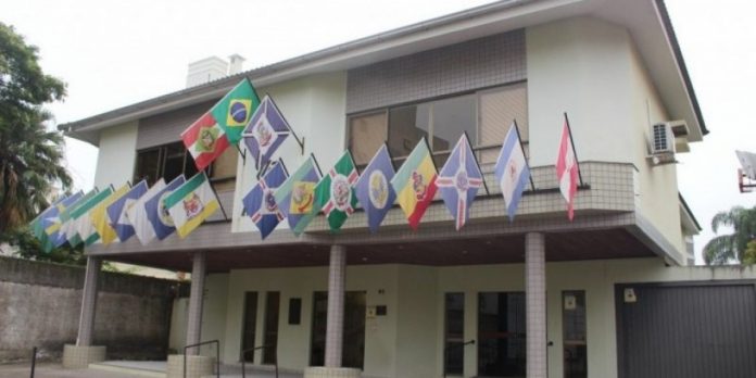 #Pracegover Foto: na imagem há um prédio e bandeiras
