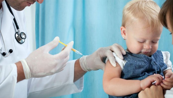 #Pracegover Foto: Na imagem um profissional aplica vacina em uma criança com aproximadamente 1 ano