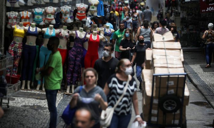 #Pracegover Foto: na imagem há pessoas caminhando, caixas e manequins