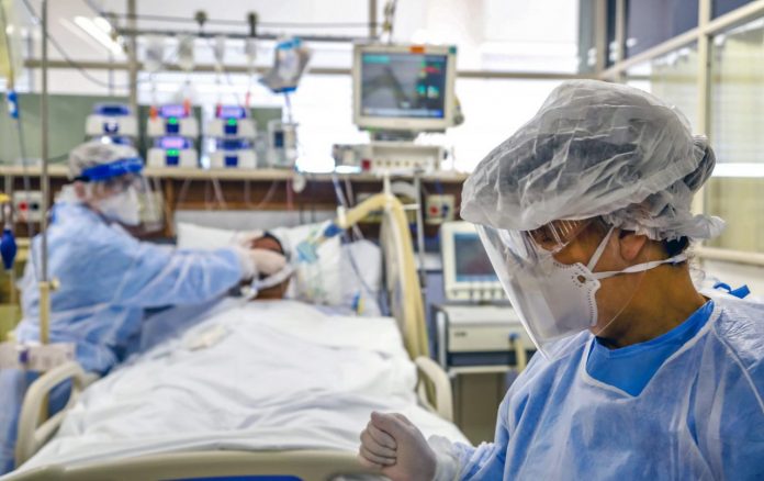 #Pracegover Foto: na imagem há uma enfermeira, um médico e o paciente em um leito de UTI