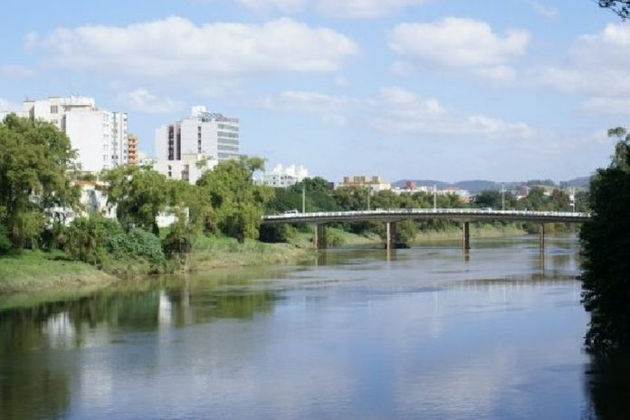#Pracegover Foto: na imagem há o uma ponte, um rio, árvores e prédios