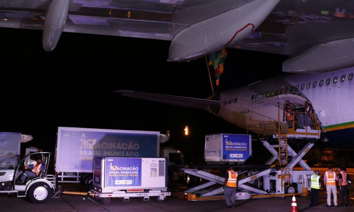 #Pracegover Foto: na imagem há caminhões, aeronave, pessoas e caixas