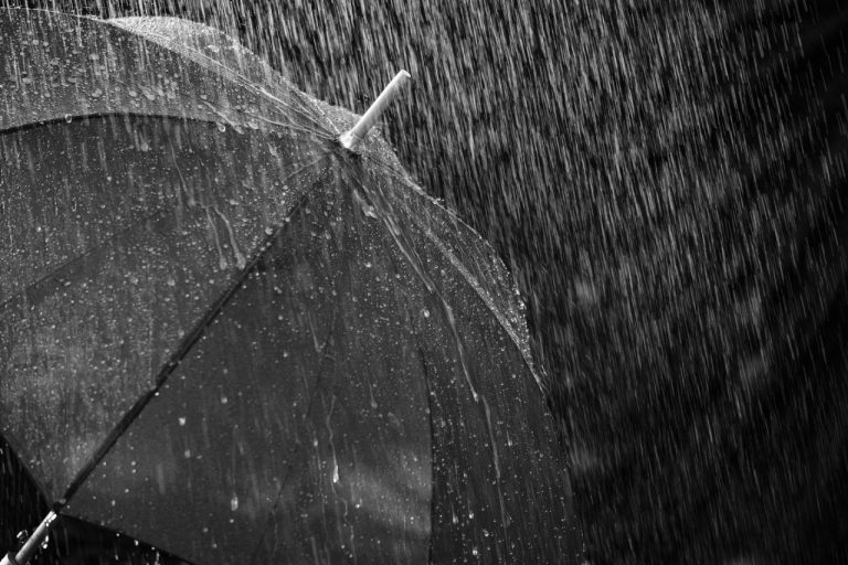#Pracegover Foto: na imagem está chovendo e tem um guarda-chuva
