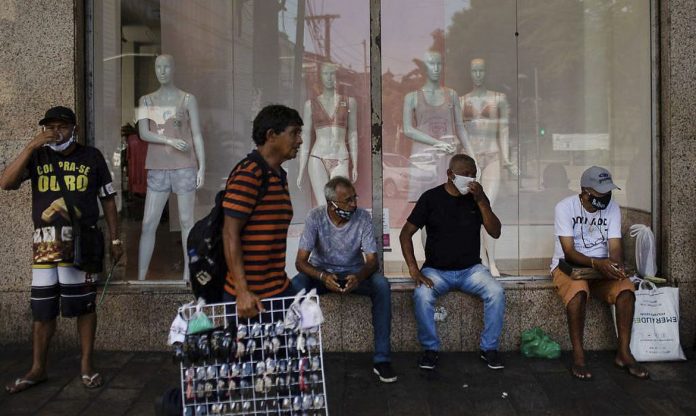#Pracegover Foto: na imagem há pessoas sentadas e um homem caminhando