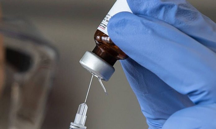 #Pracegover Foto: na imagem há um frasco de vacina, uma seringa e uma luva