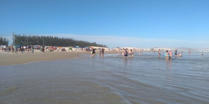 #Pracergover Foto: na imagem há o mar, faixa de areia e muitas pessoas aglomeradas