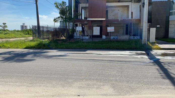 #Pracegoover Foto: na imagem há uma casa, rua e alguns matos pela calçada