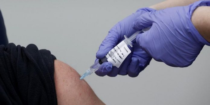 #Pracegover Foto: na imagem há uma pessoa com luvas e seringa na mão aplicando uma vacina