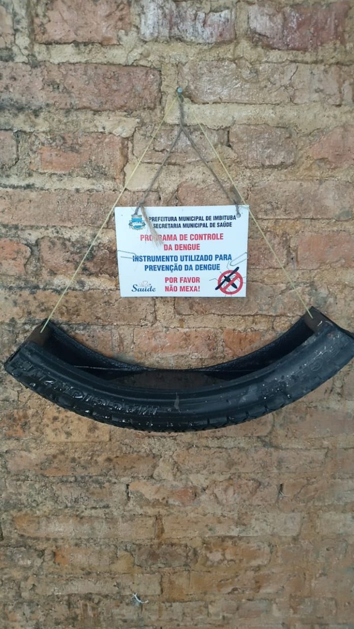 #Pracegover Foto: na imagem há uma metade de um pneu, uma parede e um cartaz