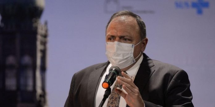 Pazuello #Pracegover Fot: na imagem há um homem de terno preto, camisa branca e de máscara. Há também um microfone