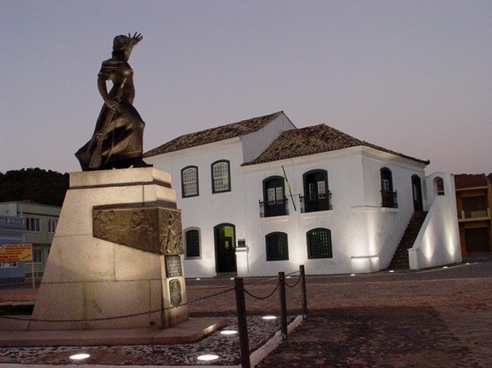 #Pracegover Foto: na imagem há um edifício e uma estátua de Anita