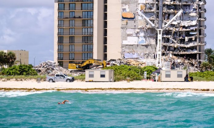 #Pracegover Foto: na imagem há um prédio, mar e destroços