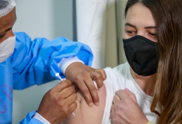 #Pracegover Foto: na imagem há uma jovem sendo vacinada