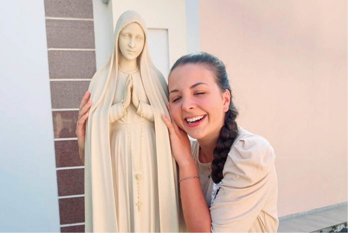 #Pracegover foto: na imagem há uma jovem abraçando uma santa