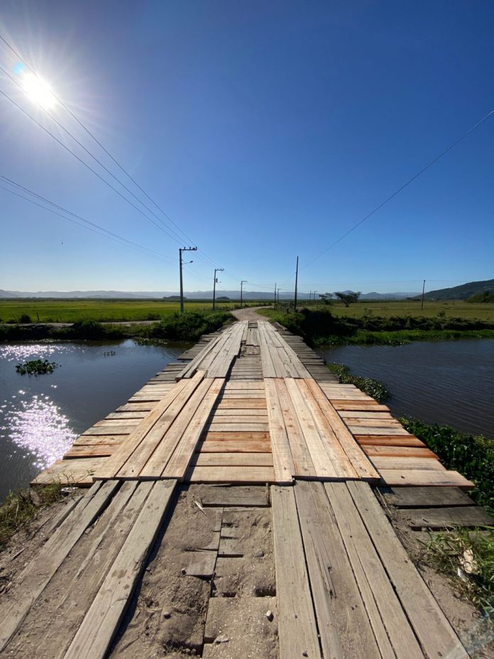 #Pracegover foto: na imagem há uma ponte, área verde e água