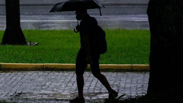 #Pracegover Na foto, homem andando com guarda-chuva em um dia chuvoso