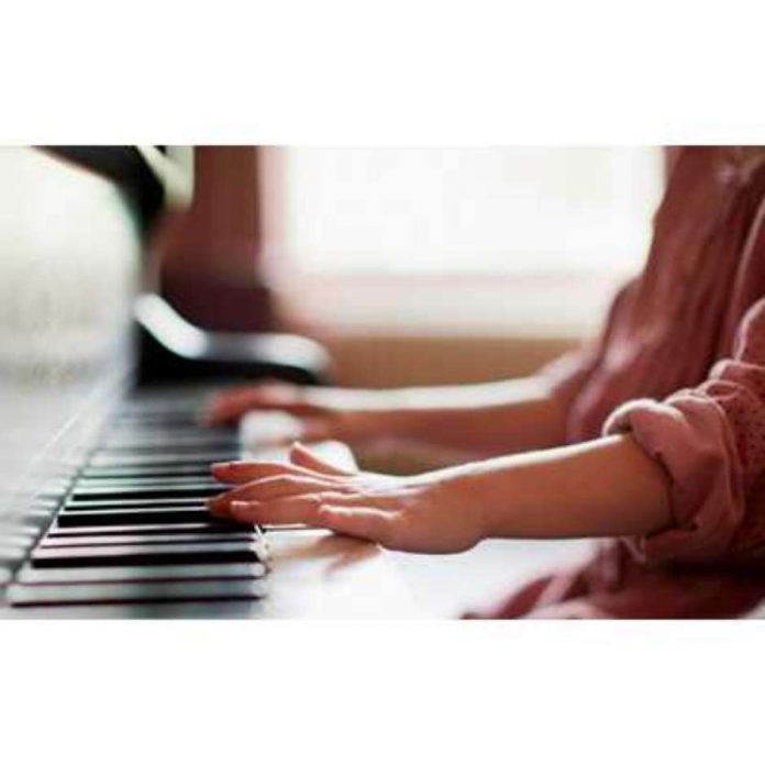 #Pracegover foto: na imagem há os braços e as mãos de uma criança e um piano