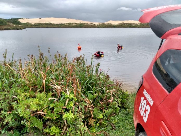 #Pracegover Foto: na imagem há uma lagoa, área verde, areia, pessoas e um veículo vermelho