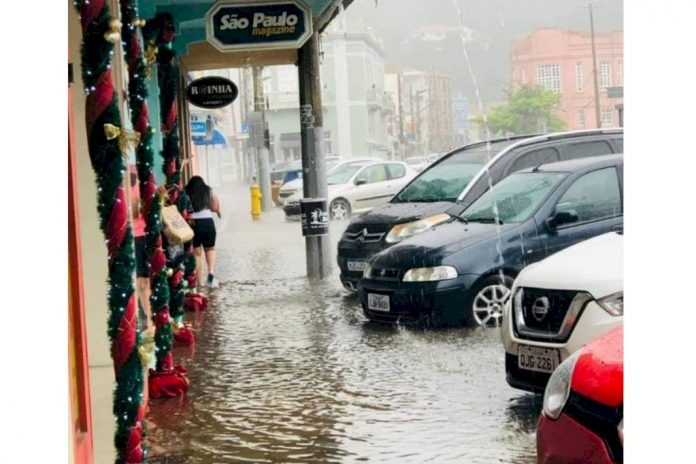 #Pracegover Foto: na imagem há carros, água, poste, placa e edifícios