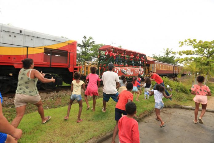 #Pracegover Foto: na imagem há crianças, adultos, trem, linha férrea e área verde