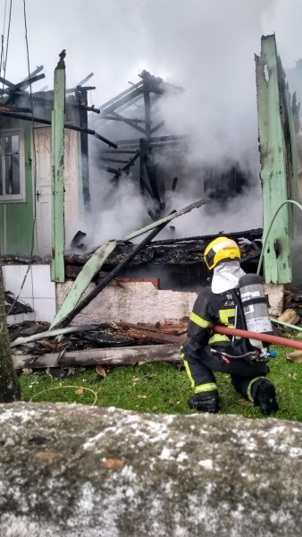 #Pracegover Foto: na imagem há um homem e uma casa em chamas