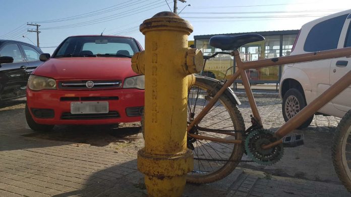 #Pracegover Foto: na imagem há um hidrante, quatro veículos, uma bicicleta, calçada e via