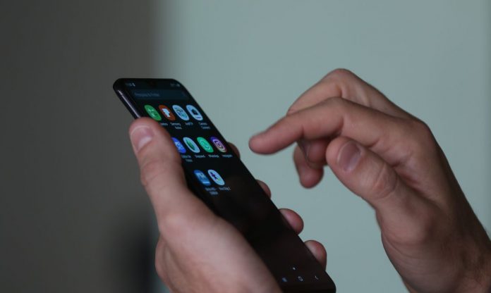 #Pracegover Foto: na imagem há um celular e duas mãos
