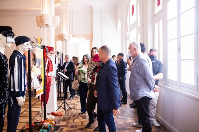 Clube Congresso #PraCegoVer Na foto, pessoas observam uma exposição de fantasias antigas de Carnaval