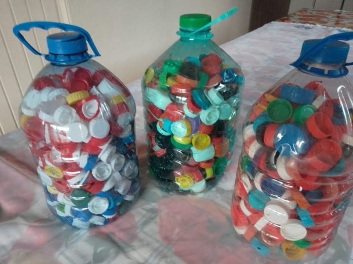 tampinhas #PraCegoVer Na foto, três garrafas cheias com tampinhas plásticas