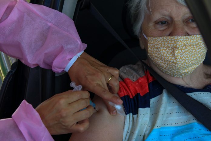 #PraCegoVer Na foto, uma idosa recebe a vacina contra a Covid-19