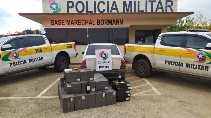#PraCegoVer Na foto, um prédio a Polícia Militar Rodoviária de Santa Catarina com três viaturas na frente várias caixas de vinhos contrabandeados