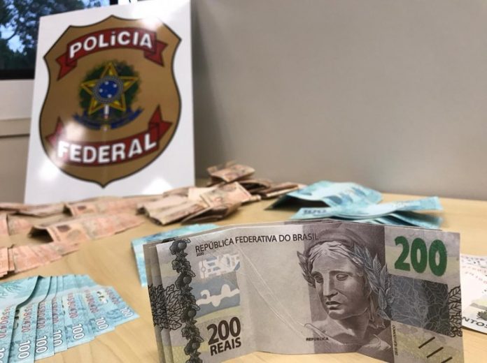 #PraCegoVer Na foto, notas de dinheiro falso e o simbolo da Polícia Federal