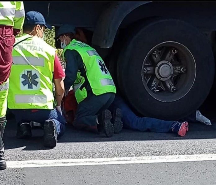#PraCegoVer Na foto, bombeiros militares resgatam motociclista que ficou preso embaixo de ronda de caminhão