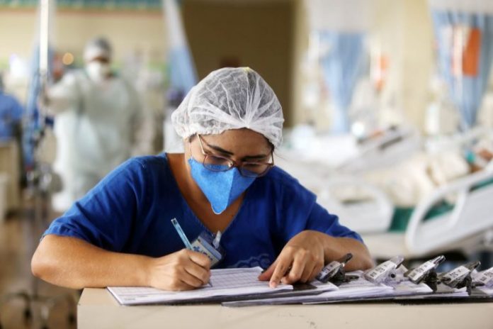 #PraCegoVer Na foto, uma enfermeira preenche informações em um papel