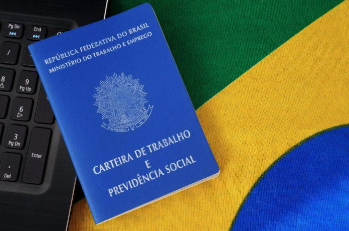 #PraCegoVer Na foto, uma bandeira do Brasil, um teclado e uma carteira de trabalho
