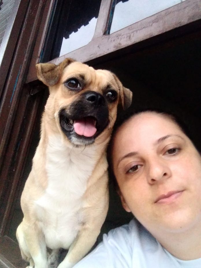 #ParaTodosVerem Na foto, um cachorro com a língua de fora e uma mulher