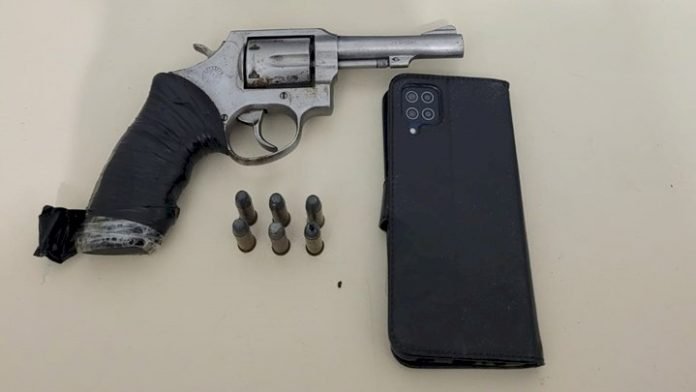 Arma Imbituba #PraCegoVer Na foto, uma arma, munições e um aparelho de telefone celular