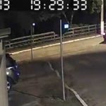 #ParaTodosVerem Na foto, uma captura feita de um vídeo de vigilância, um carro branco é visto passar por uma rua escura arrastando um cachorro de pequeno porte amarrado por um corda ao veículo