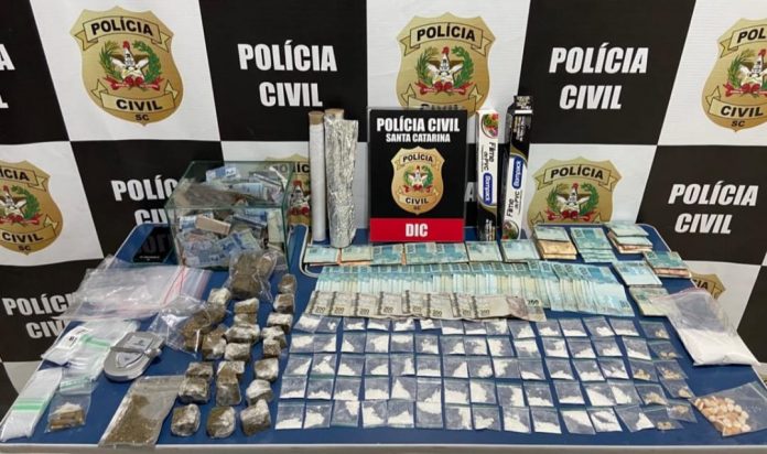 #PraCegoVer Na foto, uma mesa com drogas, dinheiro e apetrechos usados no porcionamento de entorpecentes