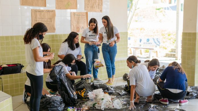 #PraCegoVer Na foto, membros do projeto EMA ensinam um grupo de alunos como separar o lixo e fazer adubo orgânico
