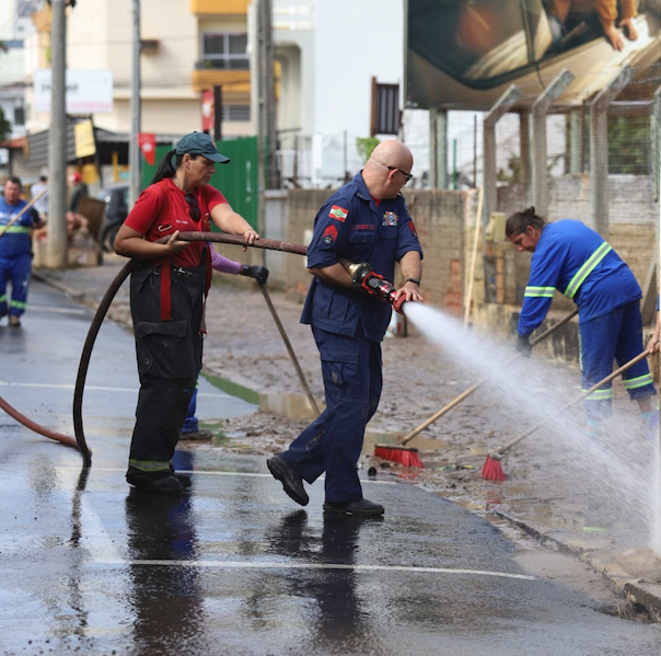 #PraCegoVer Na foto, Bombeiros militares e profissionais da Racli Limpeza Urbana fazem a limpeza das ruas centrais de Tubarão