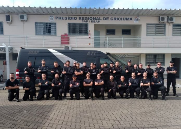 Operação_Sistema_Presídio_Regional_Criciúma #PraCegoVer Na foto, um grupo de policiais em frente de uma unidade prisional