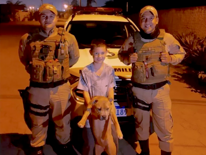 #ParaTodosVerem Na foto, há dois policiais militares, um criança e um cachorro que foi furtado e encontrado. No fundo, há a viatura da PM
