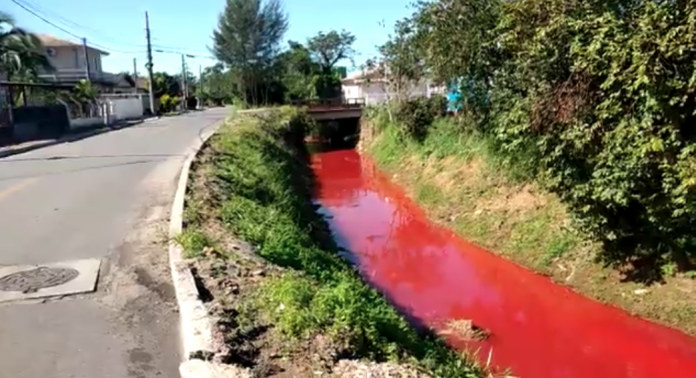 #ParaTodosVerem Na foto, um rio com a água vermelha depois que um produto químico vazou