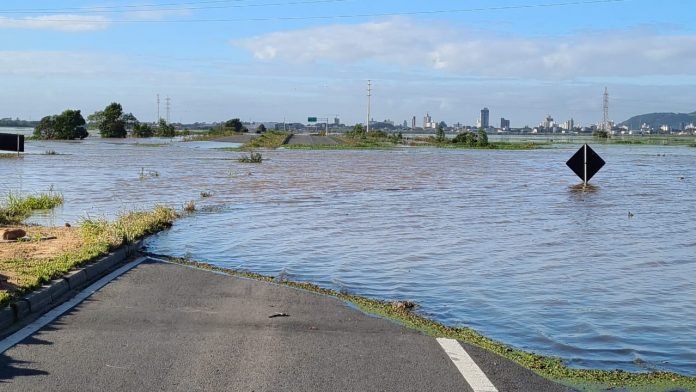 #PraCegoVer Na foto, uma estrada asfaltada coberta por um alagamento