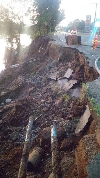 #PraCegoVer Na foto, uma estrada asfaltada danificada após o desbarrancamento da margem