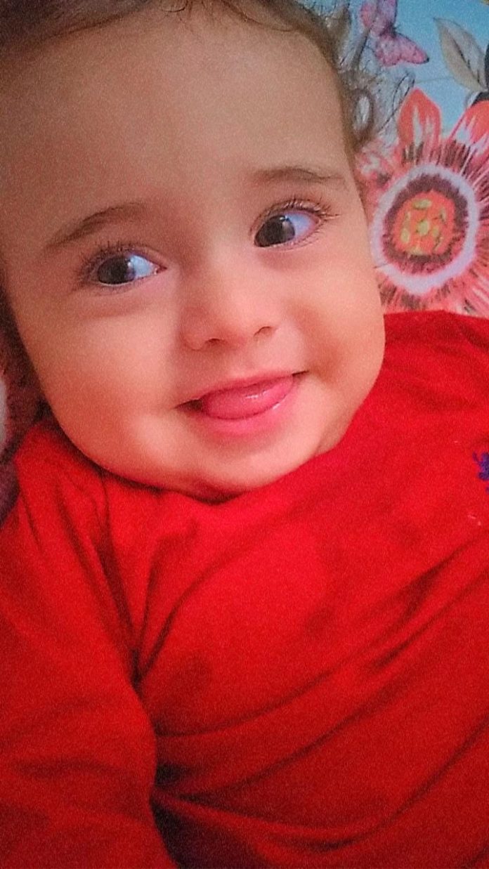 #Pracegover Foto: na imagem há um bebê com roupa vermelha
