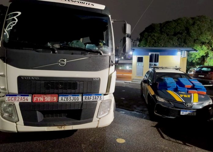 #ParaTodosVerem Na foto, um caminhão branco, quatro placas clonadas e uma viatura da Polícia Rodoviária Federal (PRF) com os tabletes de maconha encontrados dentro do veículo