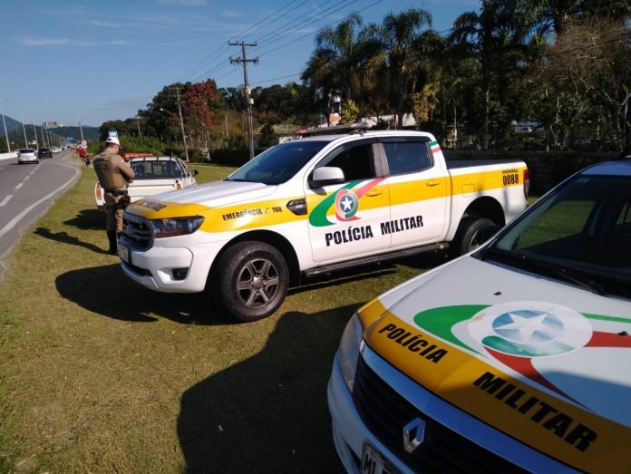 PMRv 6 #ParaTodosVerem Na foto, um policial militar rodoviário faz uma consulta ao sistema durante a abordagem de um veículo. Ele está às margens de uma rodovia estadual onde também há duas viaturas paradas