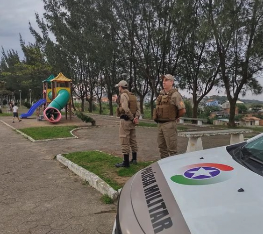#ParaTodosVerem Na foto, policiais militares fazem patrulhamento preventivo em uma praça onde há crianças brincando em um parquinho